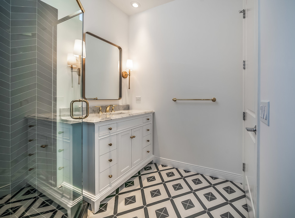 Photo of a mid-sized scandinavian master bathroom in Los Angeles with recessed-panel cabinets, white cabinets, an alcove tub, a corner shower, a one-piece toilet, white tile, ceramic tile, white walls, marble floors, an undermount sink, engineered quartz benchtops, multi-coloured floor, a sliding shower screen and grey benchtops.