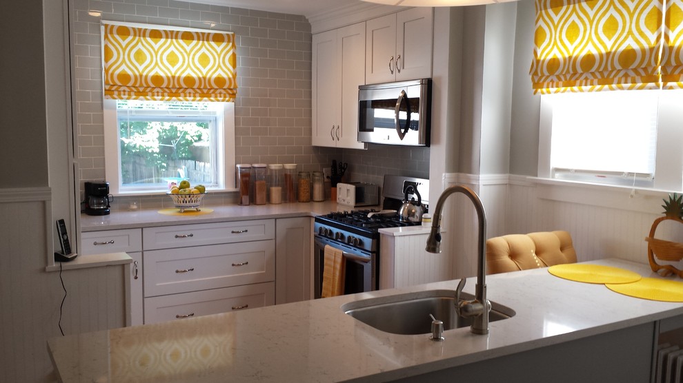 Inspiration for a small transitional u-shaped light wood floor enclosed kitchen remodel in New York with an undermount sink, shaker cabinets, white cabinets, solid surface countertops, gray backsplash, subway tile backsplash and stainless steel appliances
