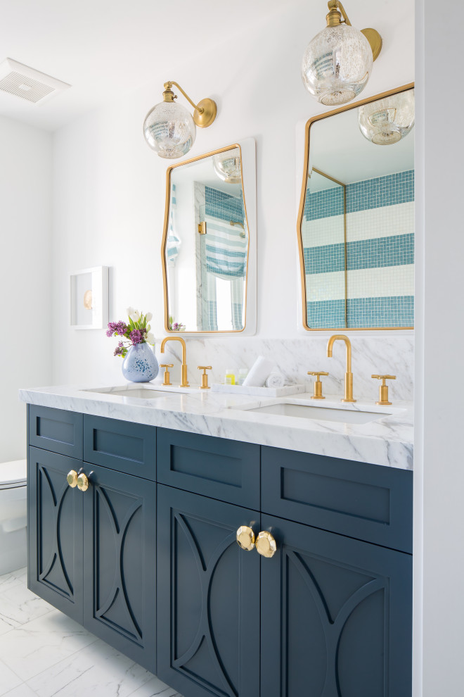 Diseño de cuarto de baño doble marinero con puertas de armario azules, baldosas y/o azulejos de vidrio y encimera de mármol