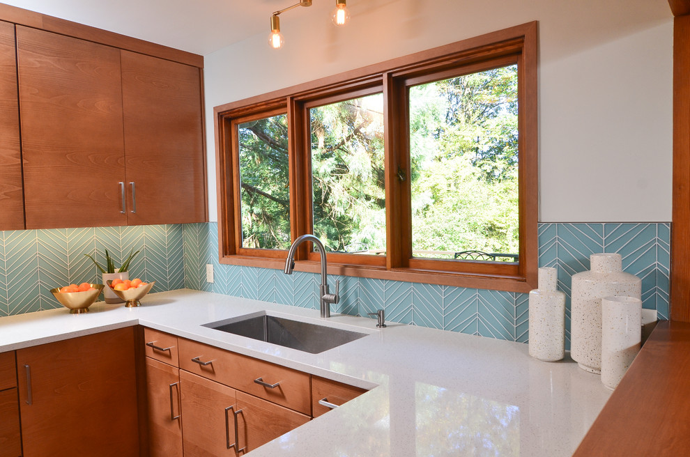 Design ideas for a mid-sized midcentury u-shaped eat-in kitchen in Portland with an undermount sink, flat-panel cabinets, medium wood cabinets, quartz benchtops, blue splashback, glass tile splashback, stainless steel appliances, a peninsula, brown floor, white benchtop and light hardwood floors.