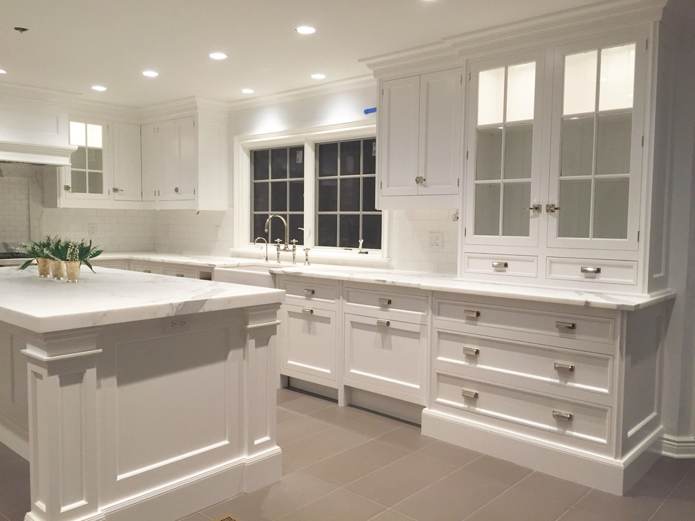 Large transitional l-shaped beige floor eat-in kitchen photo with a farmhouse sink, shaker cabinets, white cabinets, white backsplash, stainless steel appliances and an island