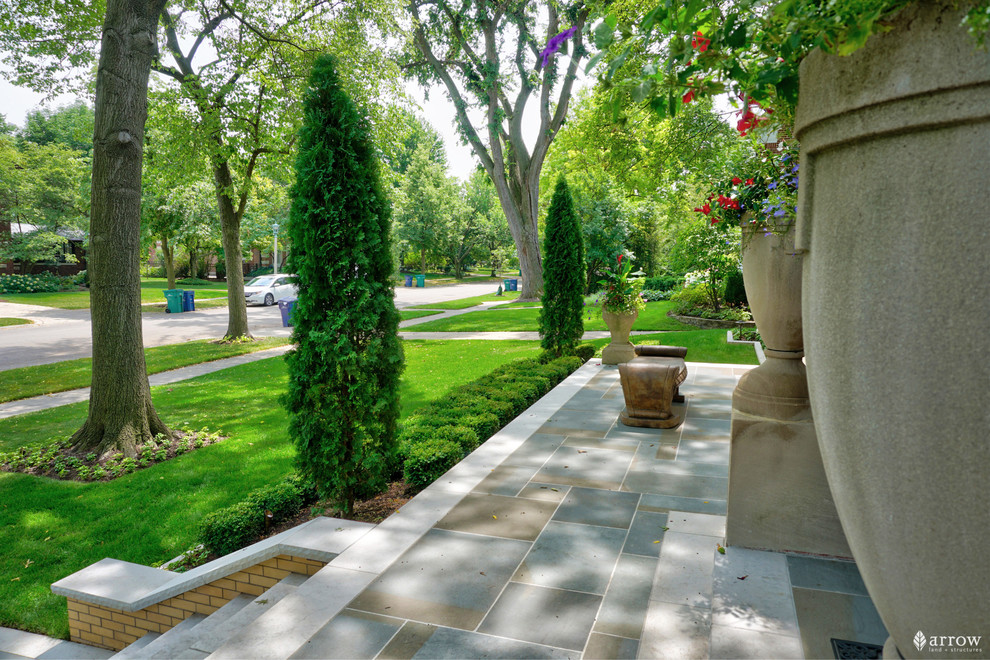 Design ideas for a large traditional front yard patio with a container garden and natural stone pavers.