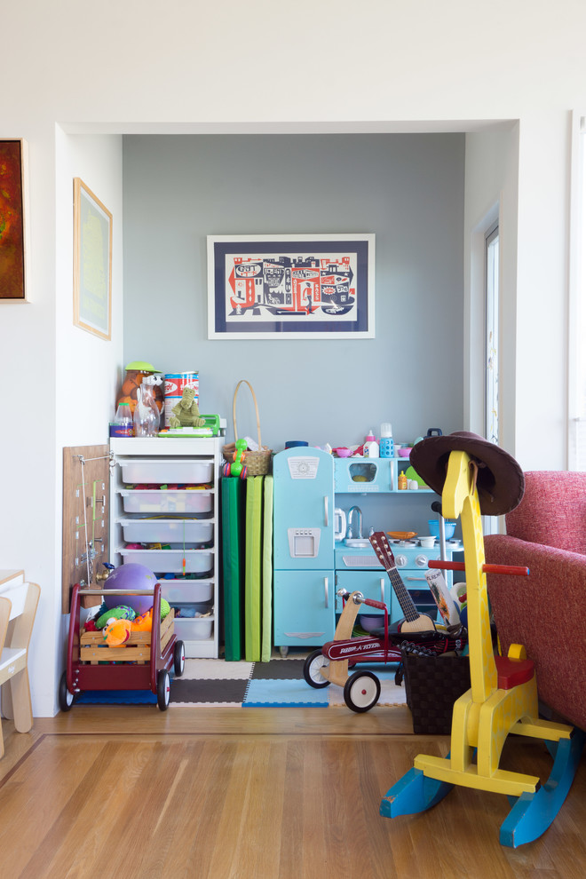 Photo of a small contemporary kids' playroom for kids 4-10 years old and girls in San Francisco with grey walls and light hardwood floors.