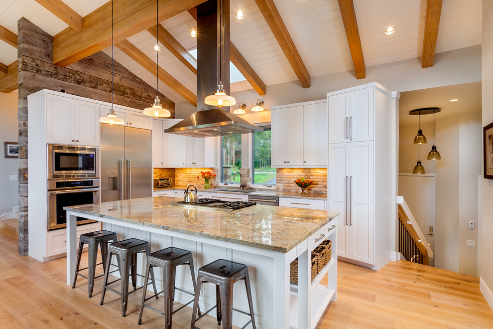 This is an example of a contemporary l-shaped kitchen in Denver with shaker cabinets, white cabinets, beige splashback, stainless steel appliances, light hardwood floors and with island.