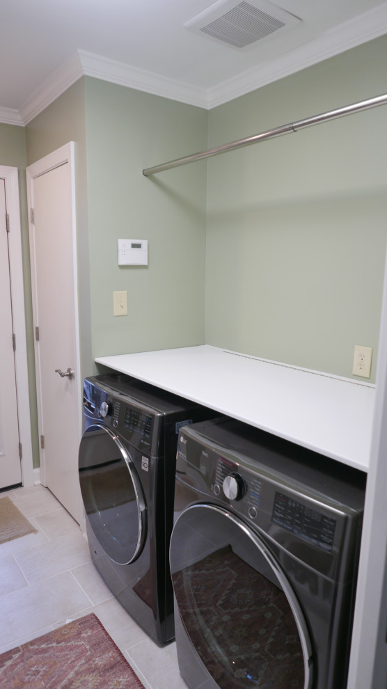Photo of a medium sized classic galley utility room in Other with shaker cabinets, white cabinets, green walls, porcelain flooring, a side by side washer and dryer and beige floors.