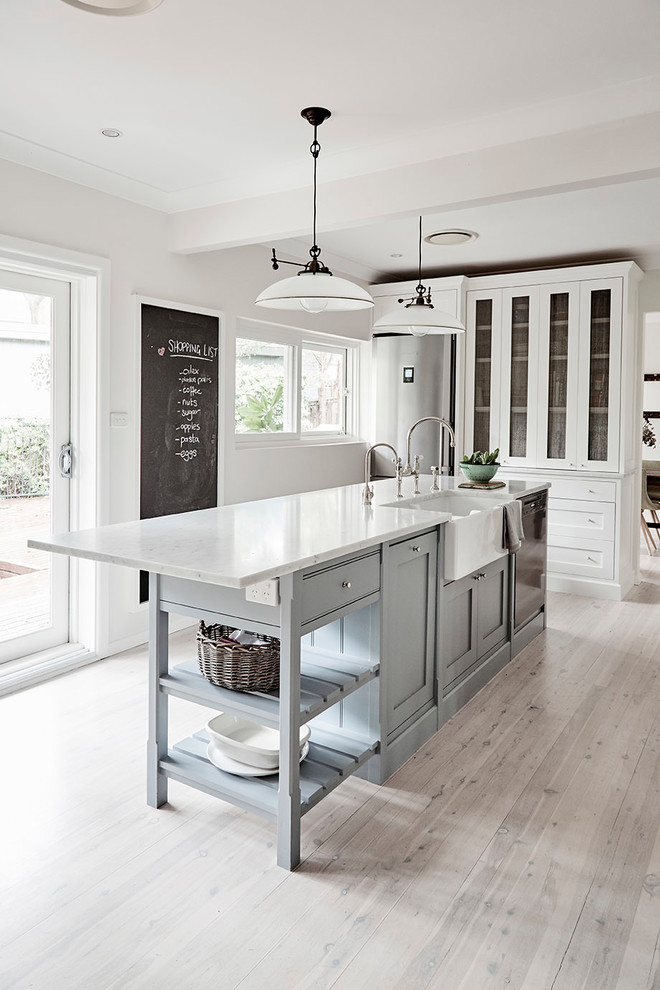 Inspiration for a mid-sized traditional u-shaped kitchen pantry in Sydney with a farmhouse sink, shaker cabinets, white cabinets, marble benchtops, white splashback, subway tile splashback, stainless steel appliances, light hardwood floors and with island.
