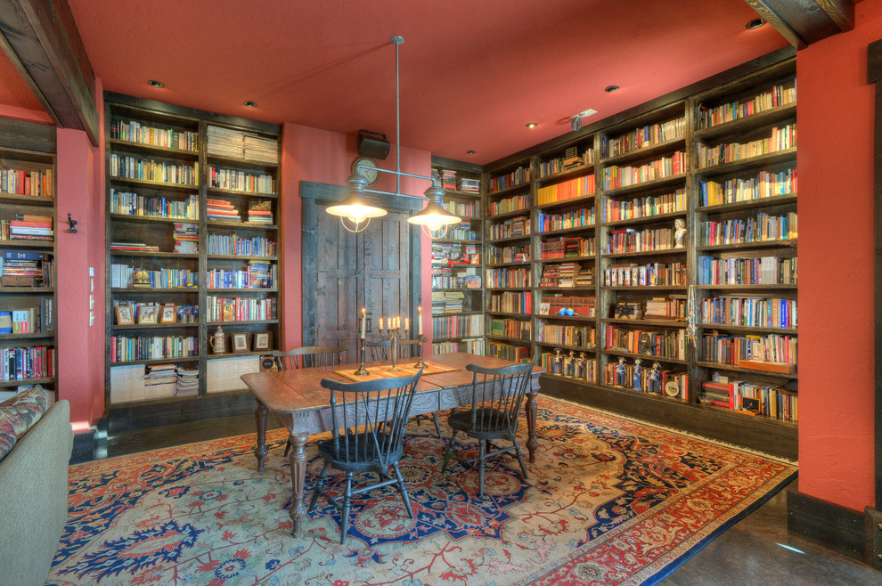 This is an example of a home office in Seattle with a library, red walls, dark hardwood floors, no fireplace and a freestanding desk.