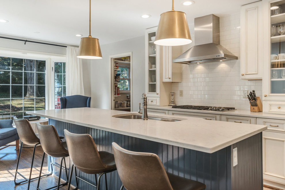 Transitional kitchen in DC Metro with an undermount sink, recessed-panel cabinets, white cabinets, white splashback, subway tile splashback, medium hardwood floors, with island, brown floor, white benchtop, granite benchtops and stainless steel appliances.
