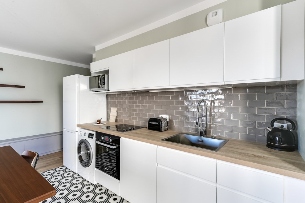 Idées déco pour une petite cuisine ouverte linéaire contemporaine avec un évier encastré, un placard à porte plane, des portes de placard blanches, un plan de travail en bois, une crédence marron, une crédence en carreau briquette et carreaux de ciment au sol.