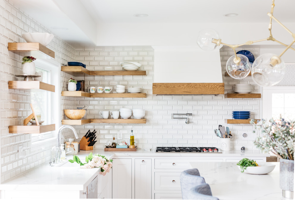 Eat-in kitchen - mid-sized transitional u-shaped medium tone wood floor and brown floor eat-in kitchen idea in Los Angeles with a farmhouse sink, recessed-panel cabinets, white cabinets, quartzite countertops, white backsplash, subway tile backsplash, stainless steel appliances, an island and white countertops