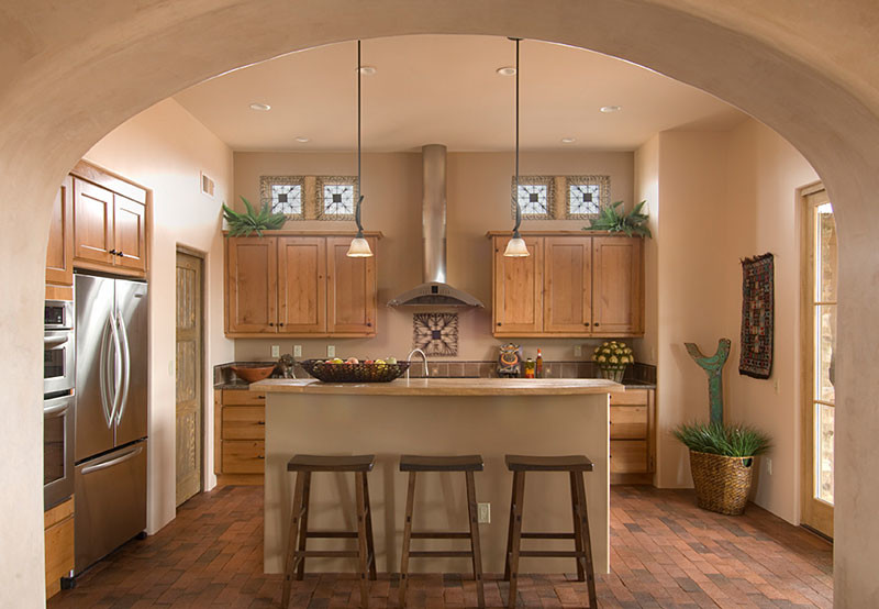 Eat-in kitchen - mid-sized rustic u-shaped brick floor and red floor eat-in kitchen idea in Albuquerque with a drop-in sink, raised-panel cabinets, light wood cabinets, wood countertops, beige backsplash, mosaic tile backsplash, stainless steel appliances and an island