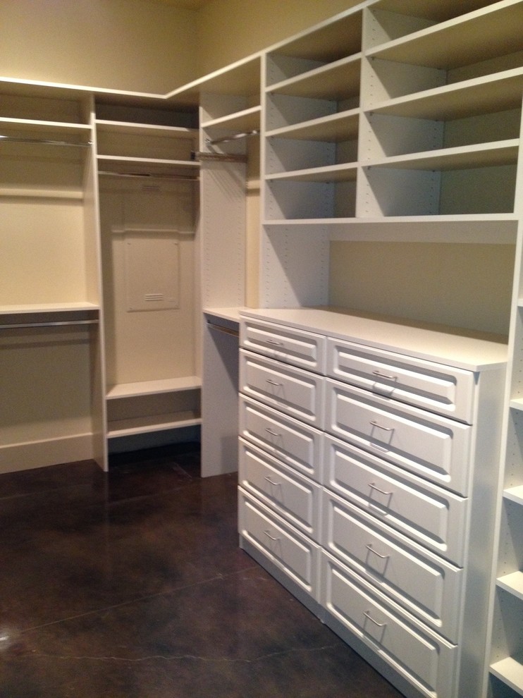 Mid-sized traditional gender-neutral walk-in wardrobe in Sacramento with raised-panel cabinets, white cabinets and concrete floors.