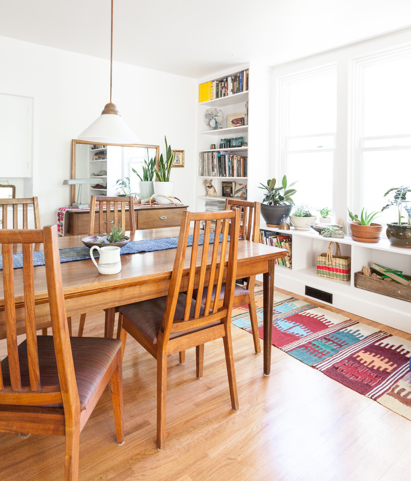 This is an example of a mid-sized eclectic kitchen/dining combo in Sacramento with white walls and light hardwood floors.