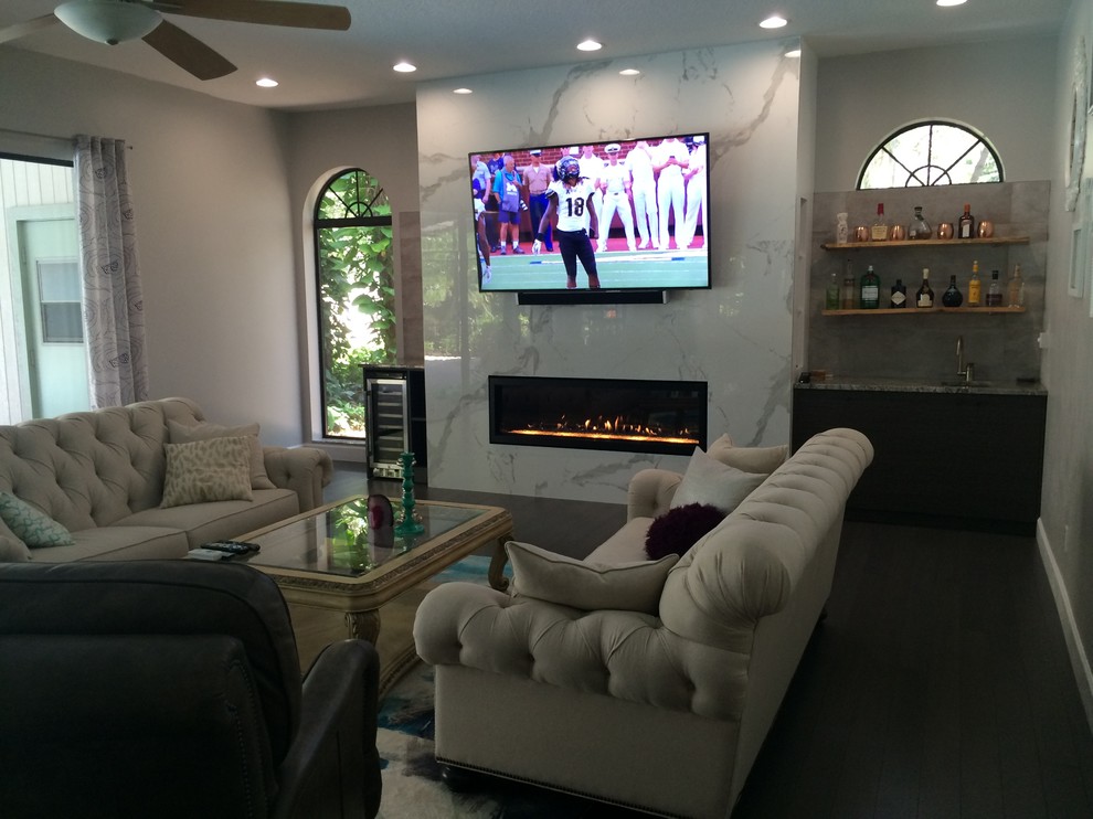 This is an example of a large contemporary open concept living room in Tampa with a home bar, grey walls, bamboo floors, a ribbon fireplace, a tile fireplace surround, a wall-mounted tv and grey floor.