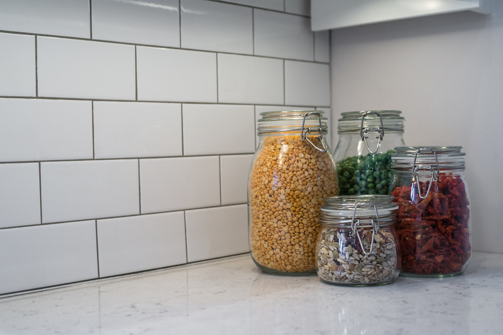 Transitional galley home design photo in Ottawa with recessed-panel cabinets, black cabinets, quartzite countertops, white backsplash, stainless steel appliances and no island