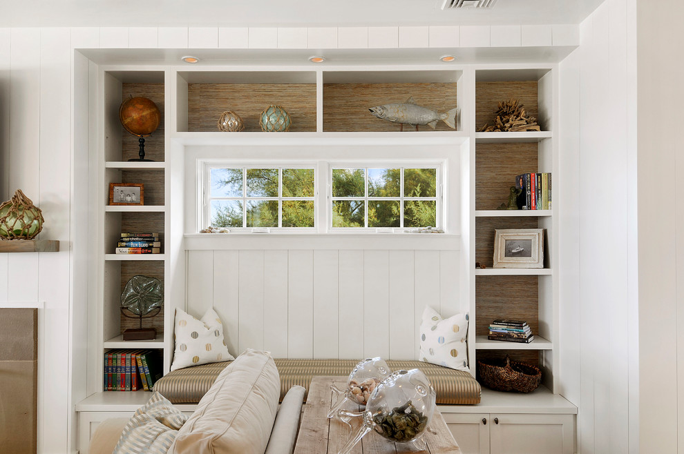 Mid-sized beach style open concept family room in Other with white walls, a library, light hardwood floors and a wall-mounted tv.
