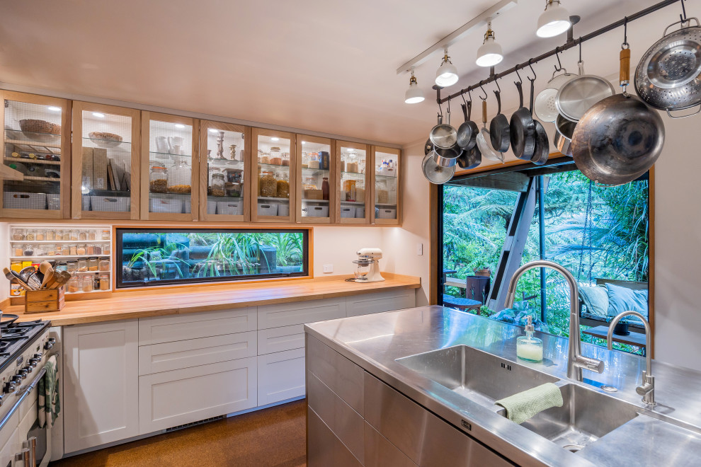 オークランドにある高級な広いエクレクティックスタイルのおしゃれなキッチン (一体型シンク、シェーカースタイル扉のキャビネット、シルバーの調理設備、コルクフローリング、茶色い床) の写真