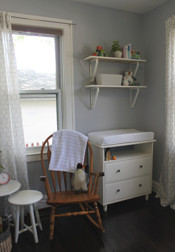 This is an example of a small modern nursery for boys in DC Metro with grey walls and dark hardwood floors.