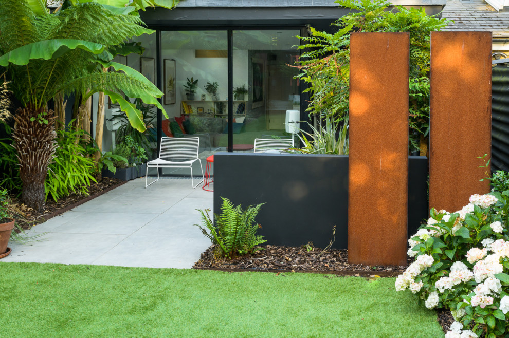 Esempio di un giardino design esposto a mezz'ombra di medie dimensioni e dietro casa con pavimentazioni in pietra naturale e recinzione in metallo