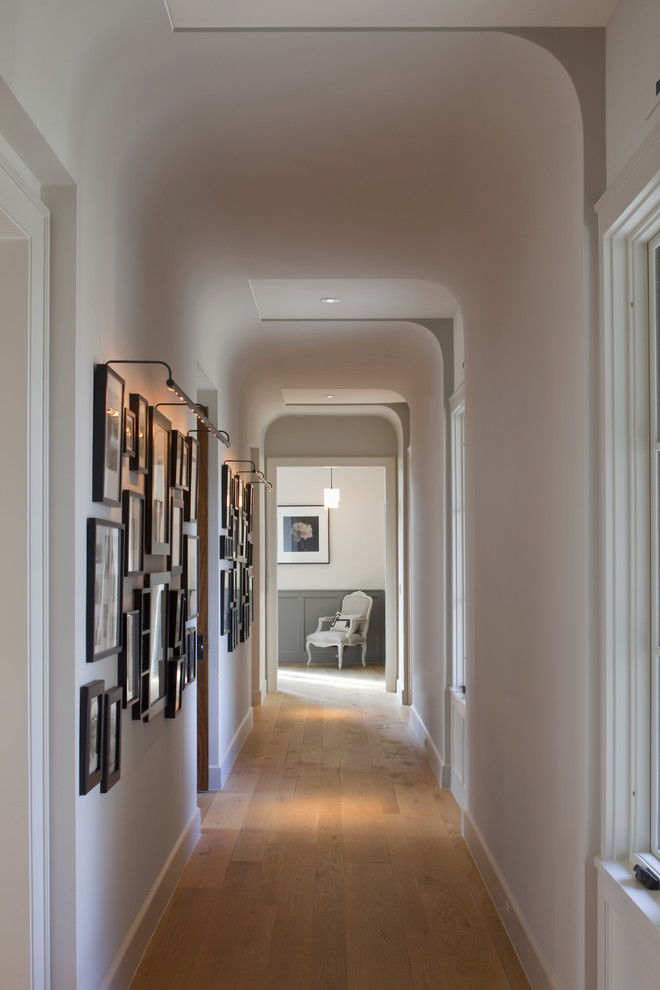 Inspiration for a traditional hallway in Austin with white walls and medium hardwood floors.