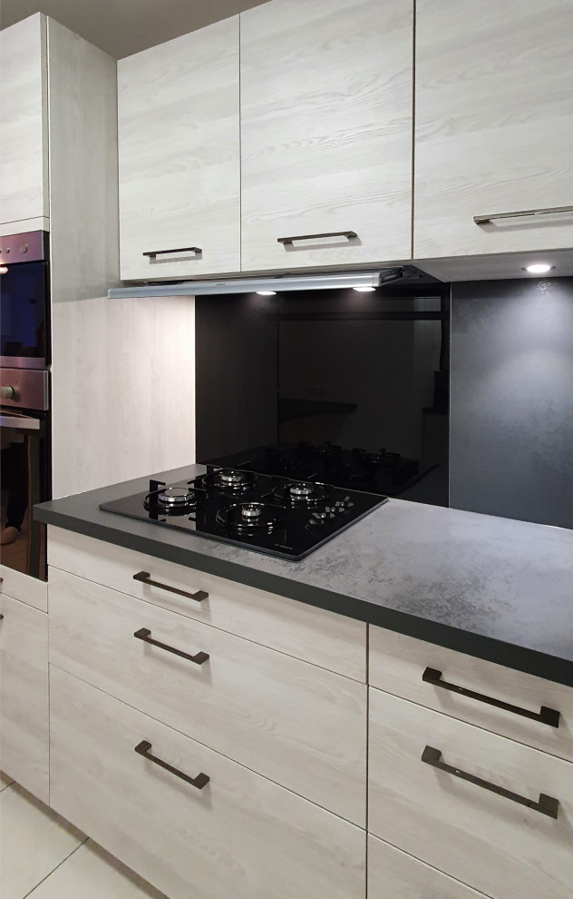 Inspiration for a medium sized contemporary l-shaped open plan kitchen in Other with a submerged sink, flat-panel cabinets, stainless steel cabinets, granite worktops, grey splashback, granite splashback, integrated appliances, cement flooring, an island, white floors and black worktops.