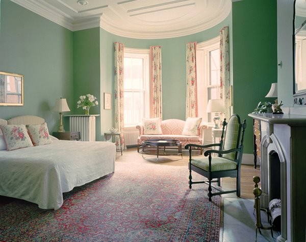 Large traditional master bedroom in Boston with green walls, medium hardwood floors, a standard fireplace and brown floor.
