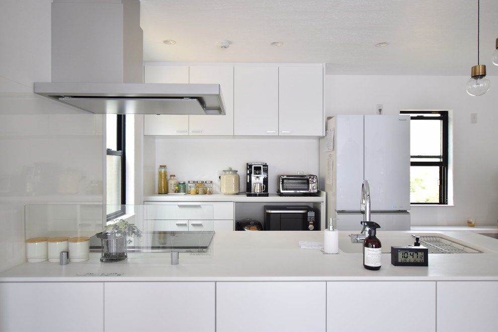 This is an example of a scandinavian galley kitchen in Other with an integrated sink, flat-panel cabinets, white cabinets, white splashback and with island.