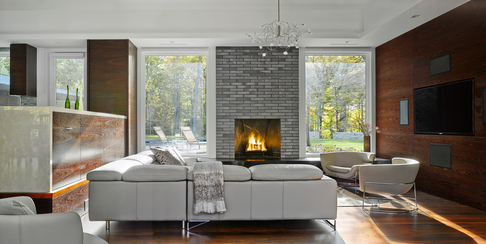 Photo of a large contemporary formal open concept living room in Burlington with a standard fireplace, a brick fireplace surround, a wall-mounted tv, laminate floors and multi-coloured walls.