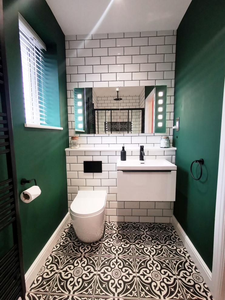 Design ideas for a small powder room in West Midlands with flat-panel cabinets, white cabinets, a one-piece toilet, white tile, ceramic tile, green walls, porcelain floors, a wall-mount sink, multi-coloured floor, white benchtops and a floating vanity.