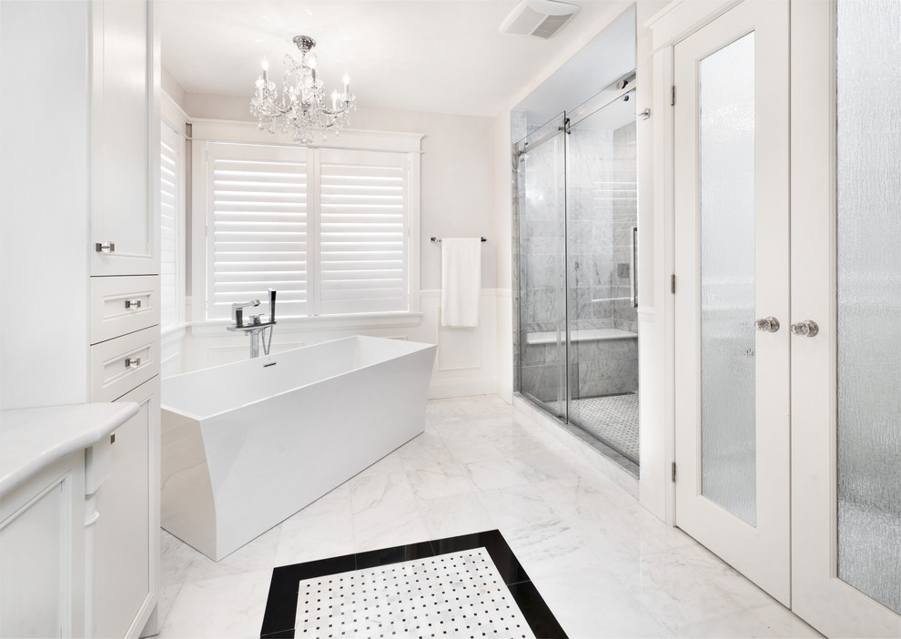 Example of a large transitional master white floor freestanding bathtub design in Ottawa with white cabinets, a two-piece toilet, white walls, an undermount sink and a hinged shower door