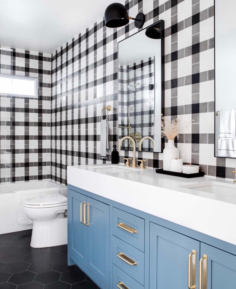 Design ideas for a small eclectic kids bathroom in Orange County with shaker cabinets, blue cabinets, a drop-in tub, a shower/bathtub combo, a one-piece toilet, black and white tile, cement tile, white walls, cement tiles, an undermount sink, quartzite benchtops, black floor, a hinged shower door and white benchtops.