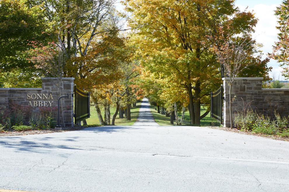 Photo of an expansive traditional front yard full sun driveway in Toronto with with a gate and a metal fence.