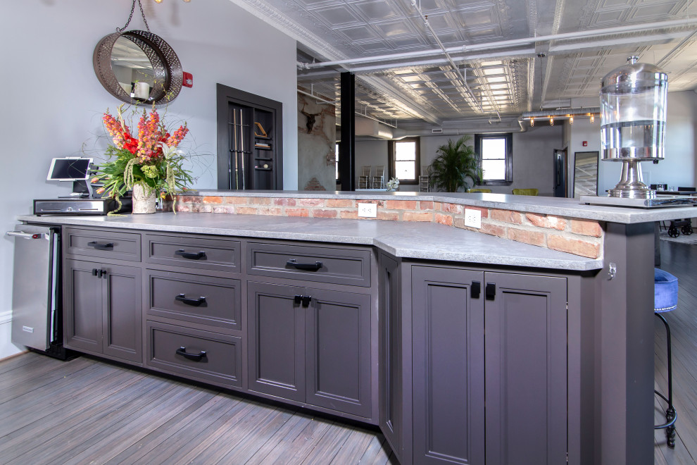 Design ideas for a large industrial seated home bar in Charlotte with beaded inset cabinets, distressed cabinets, concrete benchtops, grey splashback, brick splashback, medium hardwood floors, grey floor and grey benchtop.