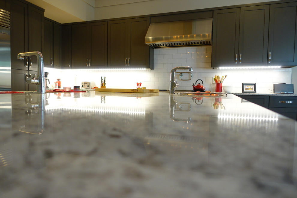 Inspiration for a large transitional l-shaped medium tone wood floor and brown floor eat-in kitchen remodel in Atlanta with an undermount sink, shaker cabinets, gray cabinets, granite countertops, white backsplash, subway tile backsplash, stainless steel appliances and an island