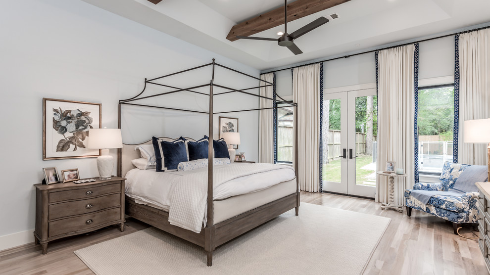 This is an example of an expansive transitional master bedroom in Houston with light hardwood floors, beige floor and grey walls.