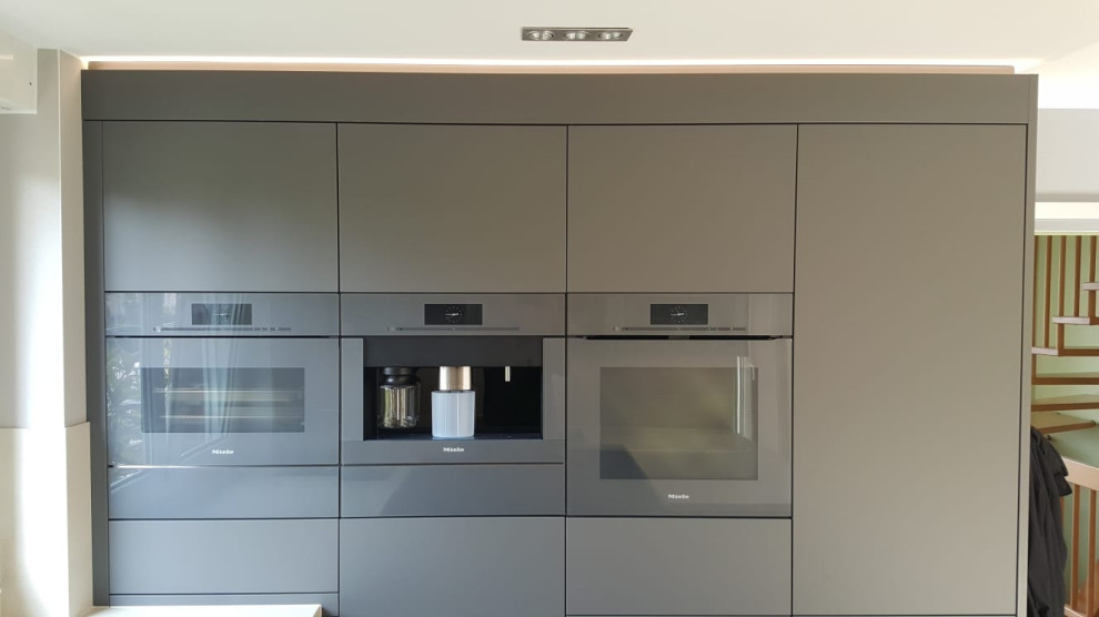 Photo of a mid-sized contemporary u-shaped open plan kitchen in Berlin with a single-bowl sink, flat-panel cabinets, grey cabinets, tile benchtops, beige splashback, ceramic splashback, panelled appliances, porcelain floors, a peninsula, grey floor and beige benchtop.
