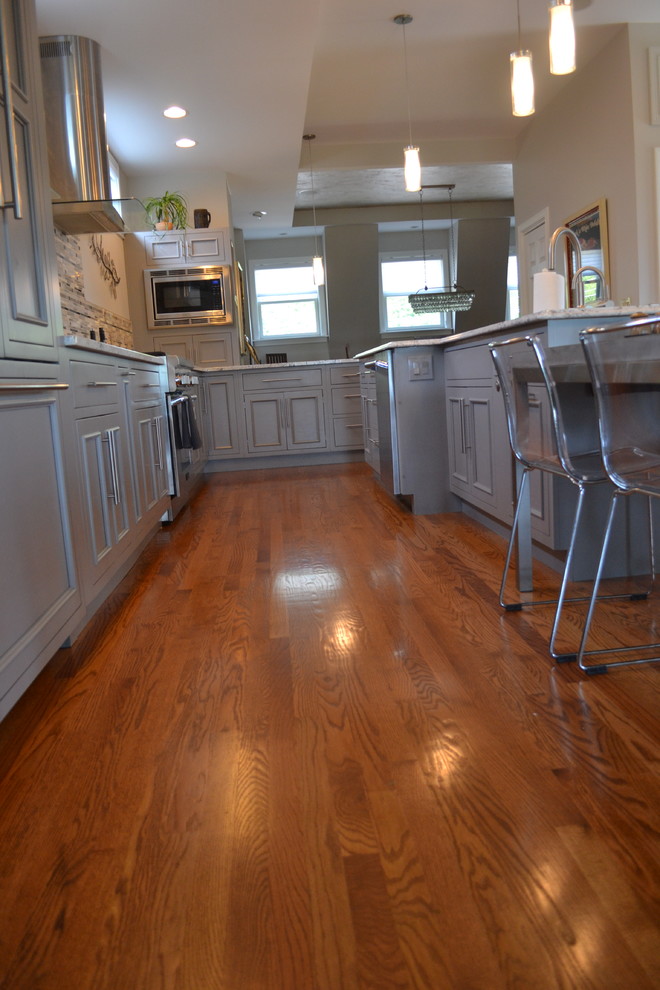 Open concept kitchen - large transitional l-shaped medium tone wood floor open concept kitchen idea in Cincinnati with an undermount sink, gray cabinets, granite countertops, multicolored backsplash, mosaic tile backsplash, stainless steel appliances, an island and beaded inset cabinets
