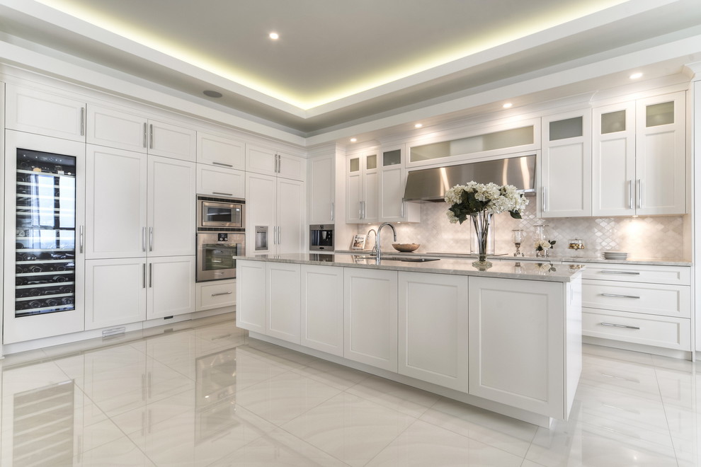 Inspiration for a mid-sized contemporary u-shaped marble floor and white floor open concept kitchen remodel in Montreal with an undermount sink, shaker cabinets, white cabinets, marble countertops, white backsplash, stone tile backsplash, stainless steel appliances and an island