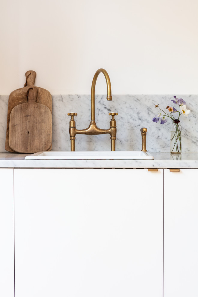 Esempio di una cucina abitabile minimalista di medie dimensioni con ante lisce, ante bianche, top in marmo, nessuna isola e top bianco