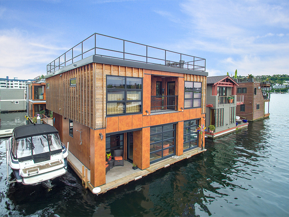 This is an example of an expansive industrial two-storey orange house exterior in Seattle with wood siding and a flat roof.
