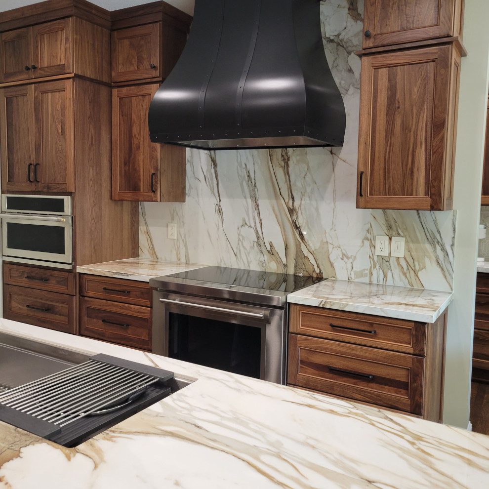 Large transitional medium tone wood floor and brown floor kitchen photo with an undermount sink, recessed-panel cabinets, medium tone wood cabinets, multicolored backsplash, stainless steel appliances, an island and multicolored countertops