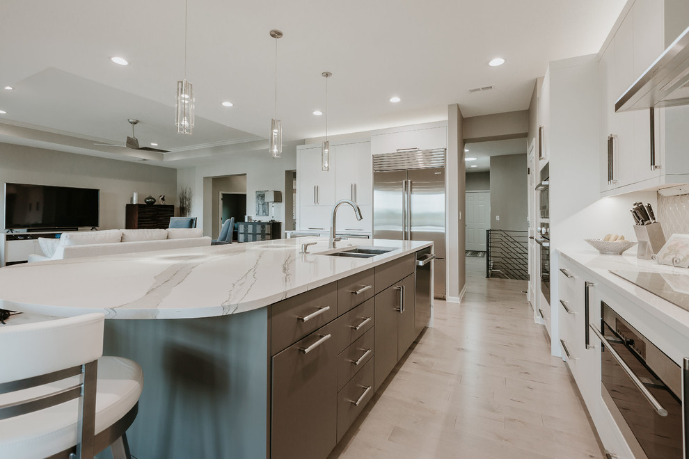 This is an example of a mid-sized contemporary l-shaped kitchen in Other with an undermount sink, flat-panel cabinets, quartzite benchtops, grey splashback, ceramic splashback, stainless steel appliances, light hardwood floors, with island, grey floor and grey benchtop.