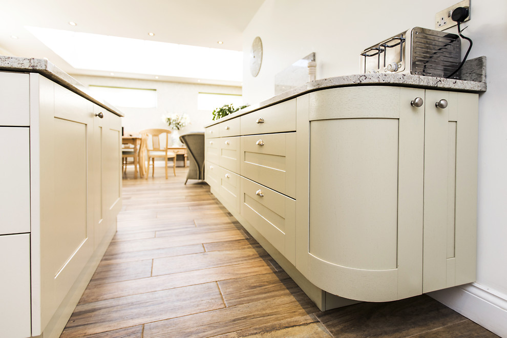 This is an example of a large traditional galley eat-in kitchen in Hampshire with an undermount sink, shaker cabinets, green cabinets, granite benchtops, stainless steel appliances, porcelain floors, with island, beige floor and beige benchtop.