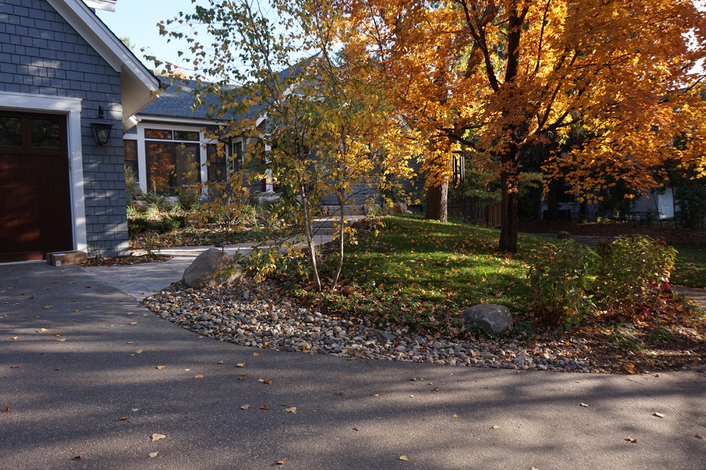 This is an example of a mid-sized rustic partial sun front yard stone driveway in Minneapolis.
