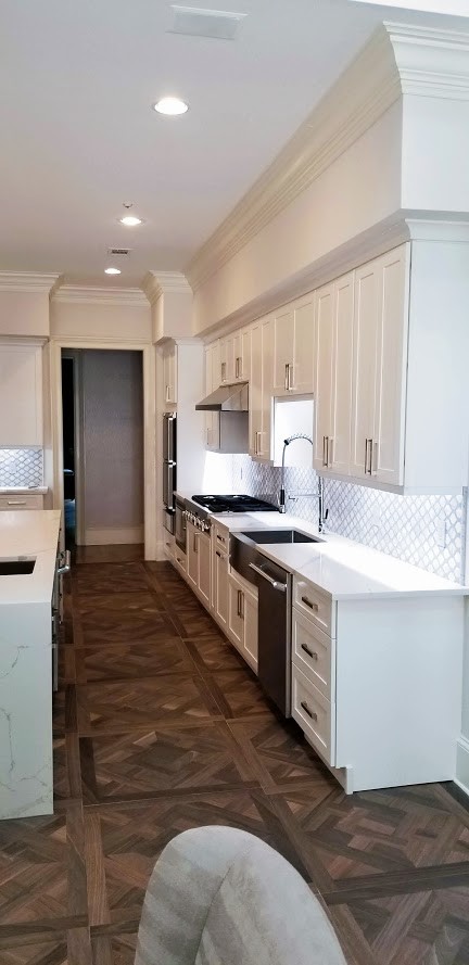 Large transitional u-shaped dark wood floor and brown floor eat-in kitchen photo in Miami with a farmhouse sink, shaker cabinets, white cabinets, stainless steel appliances, an island, white countertops, marble countertops and gray backsplash