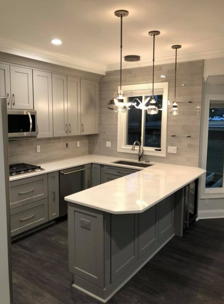Inspiration for a transitional u-shaped gray floor kitchen remodel with an undermount sink, recessed-panel cabinets, gray cabinets, gray backsplash, stainless steel appliances and white countertops
