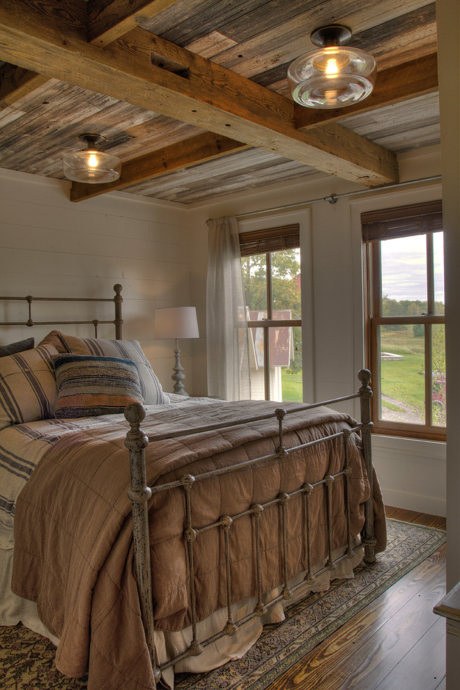 Inspiration for a mid-sized country guest bedroom in Minneapolis with white walls, medium hardwood floors and brown floor.