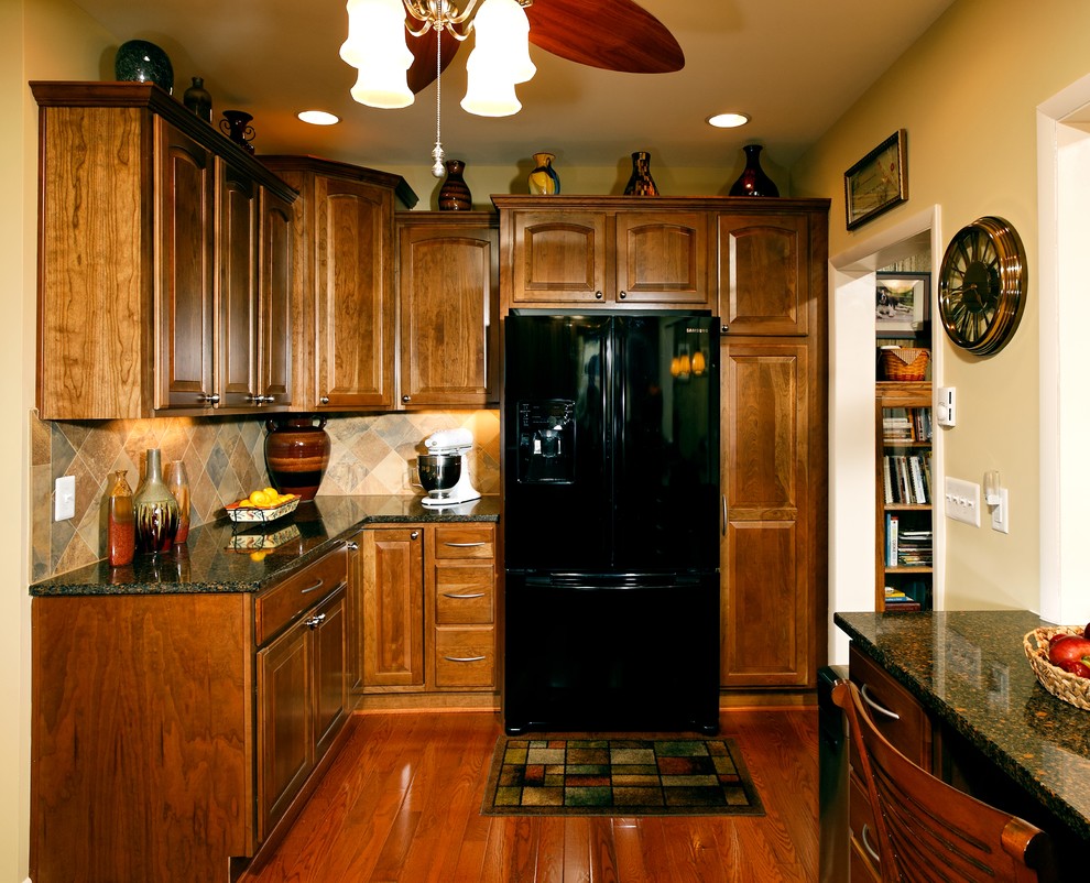 Inspiration for a transitional l-shaped eat-in kitchen remodel in DC Metro with furniture-like cabinets, medium tone wood cabinets, granite countertops, beige backsplash, mosaic tile backsplash and black appliances