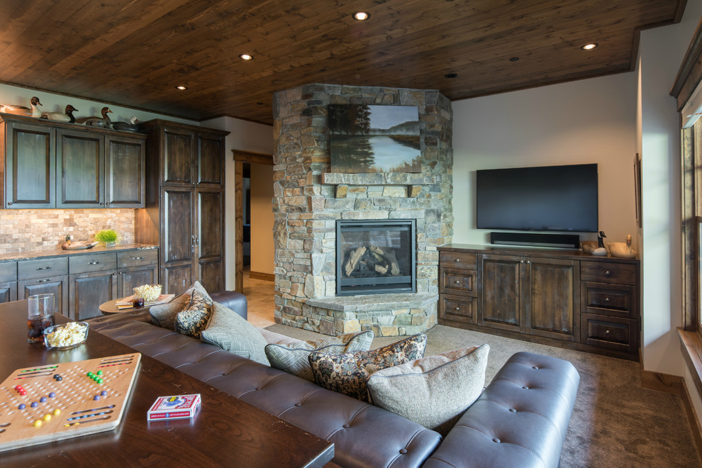 This is an example of a large country walk-out basement in Minneapolis with beige walls, carpet, a corner fireplace, a stone fireplace surround and brown floor.