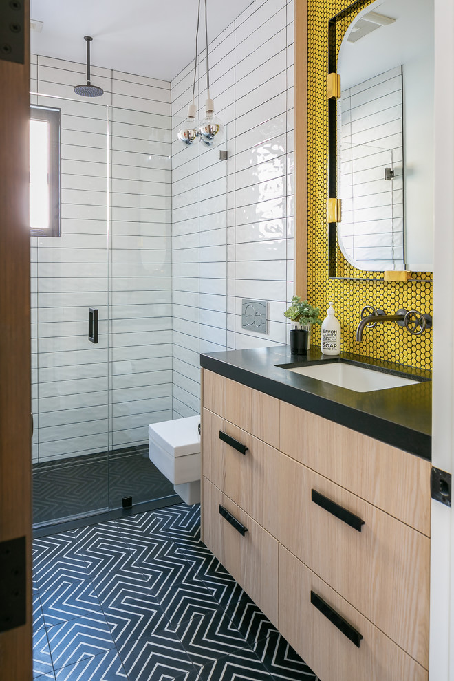 Inspiration for a contemporary 3/4 bathroom in Orange County with flat-panel cabinets, light wood cabinets, a curbless shower, a wall-mount toilet, white tile, yellow tile, mosaic tile, an undermount sink, black floor, a hinged shower door and black benchtops.
